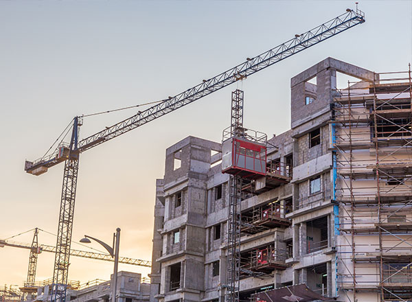 A building under construction with cranes in the background.