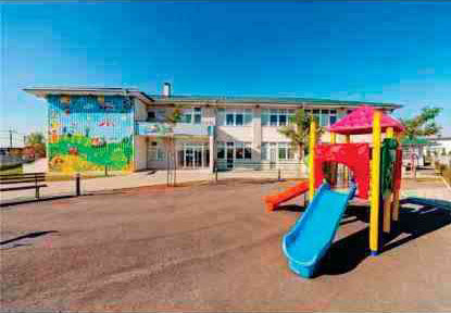 A playground with slides and a slide in front of a building.